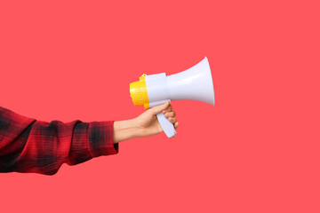 Female hand with megaphone on red background