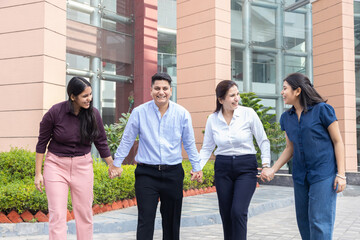 Obraz premium Happy young indian entrepreneur, office employees celebrating achievement outdoors, Teamwork and unity, Business and finance.
