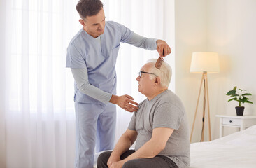 Young caregiver assisting senior man with his daily grooming routine in bright bedroom. Friendly...