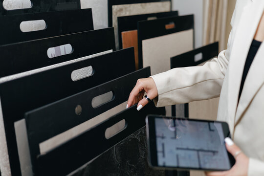 Woman interior designer selecting materials in showroom with digital tablet