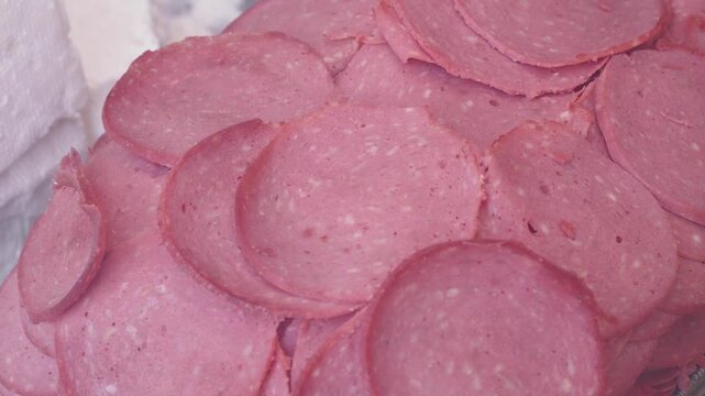 Heap of thinly sliced salami arranged on a platter, serving as a delicious food background