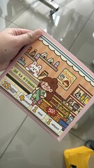 Illustrated Storybook in Hand: A close-up view of a hand holding a captivating illustrated storybook, revealing colorful artwork and a playful scene, hinting at a world of imagination and adventure.