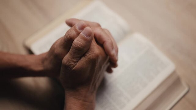 Old man hands clasped prayer with Holy Bible for Christian faith, spirituality, worship, devotion, hope, and religious belief, prayer time in church, trust in God, and spiritual guidance.