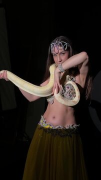 Belly Dancer Posing with Albino Python in Dark Studio
