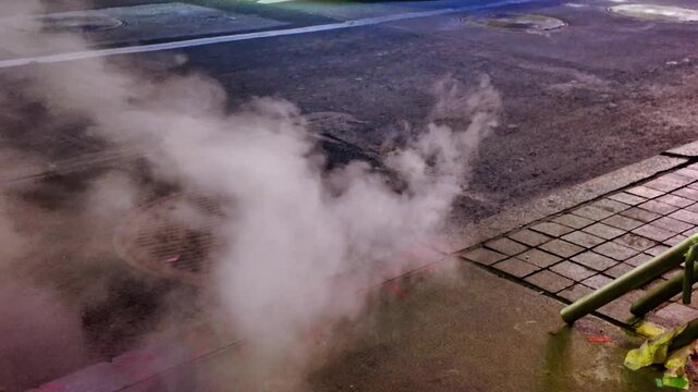 Steam rising from a manhole cover on a New York City street at night. Steam is visible coming from a manhole on a street in New York City.