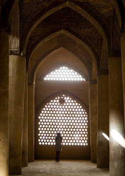 Woman looking thru the window of the friday mosque, Isfahan province, Isfahan, Iran