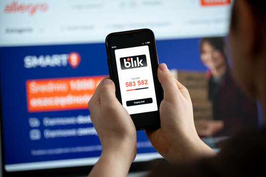 Woman uses a smartphone to make a BLIK payment. Mobile screen displays the Blik logo and a six-digit code field, Allegro e-commerce website with Smart in bg on February 17, 2026 in Krakow, Poland.