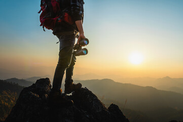 man is standing on a mountain top with a pair of binoculars in his hands