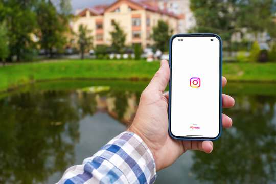 Person using a smartphone with the Instagram splash screen open, showing the logo and Meta copyright, in a park setting