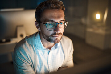 Obraz premium Reading, computer and glasses with business man in office for planning, night and it web system. Overtime, research and project manager with employee in tech agency for operations launch or developer