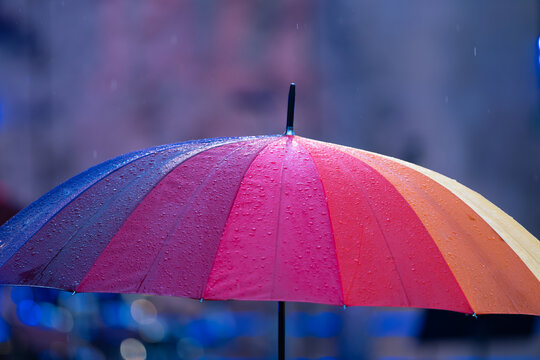 Un parapluie color&eacute; ouvert sous la pluie