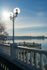 Fototapeta premium Serene waterfront view with white balustrade and spherical lamps across calm Black sea under clear sky in Gelendzhik