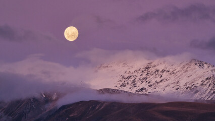 Moon Rising Over Snowcapped Mountain