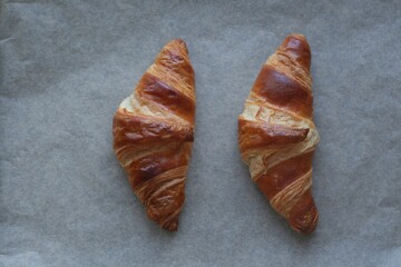two butter croissants on parchment photographed from above