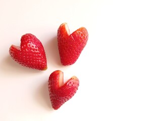 Close up of three heart shaped strawberries isolated in white.
