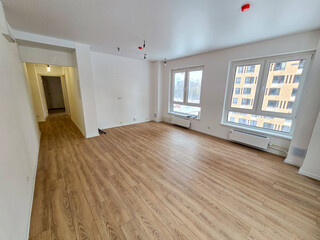 Obraz premium A large empty room with a wooden floor and a white wall. The room is empty and has no furniture