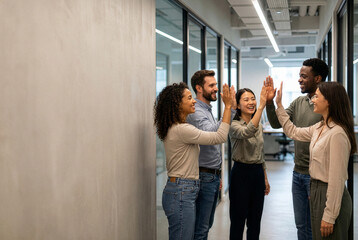 Obraz premium Diverse Coworkers Celebrating With High Fives In Modern Office