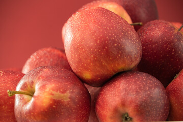 Abundance of fresh picked apples. Fresh Red Apples on red background. A bountiful close-up view of shiny red apples, neatly arranged, emphasizing their fresh and juicy appearance.