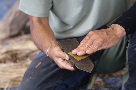 左官コテの手入れをする男性