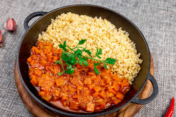 Bulgur Pilaf with Stewed Vegetables (Carrots, Tomato Sauce) in Cast Iron Skillet: Vegan Dish with...
