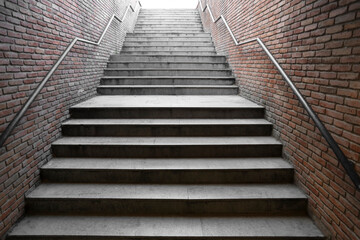 Fototapeta premium new modern empty underground passage stone stairway descending into a brick-walled tunnel. metal iron railings. underground concrete stair with brown brick wall Tbilisi Georgia