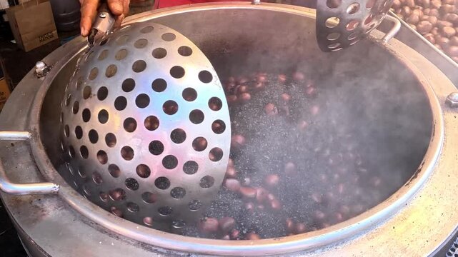Close-up of a traditional street food vendor  , showing a motorized tumbler roasting Chinese chestnuts , street food Chiangmai Thailand.