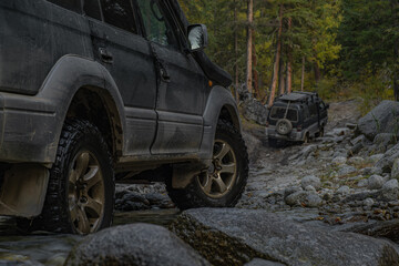 Off-road 4x4 vehicles driving through rocky river stream and muddy forest road during extreme mountain expedition adventure. © ANDREY