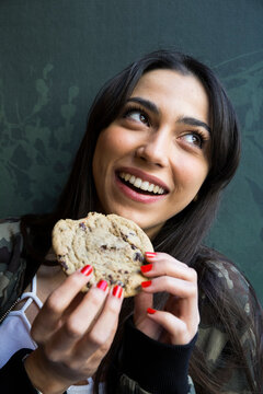 Smiling woman looking sideways and eating cookie