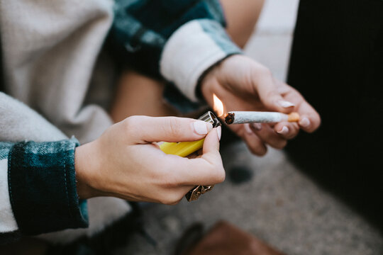 Close-up of a woman's hands lighting a marijuana joint