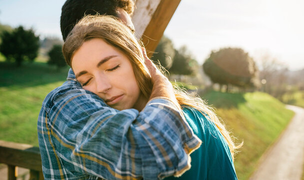 Portrait of young woman with eyes closed with head on shoulder of her boyfriend