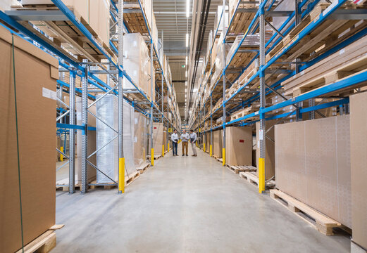 Three men standing in factory warehouse