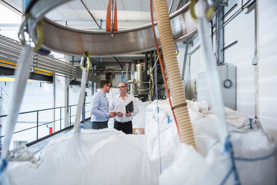 Two men talking about materials in factory