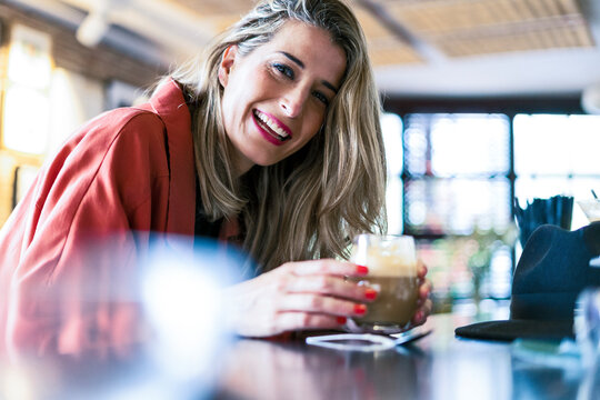 Portrait of happy woman having a drink at the counter of a bar