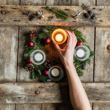 Hand of woman touching glass cover of candle burning on Advent wreath