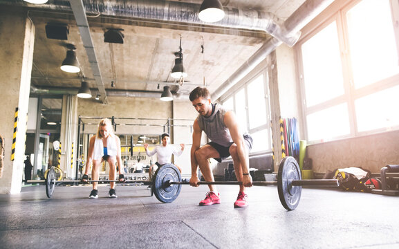 Group of young fit people weightlifting in gym