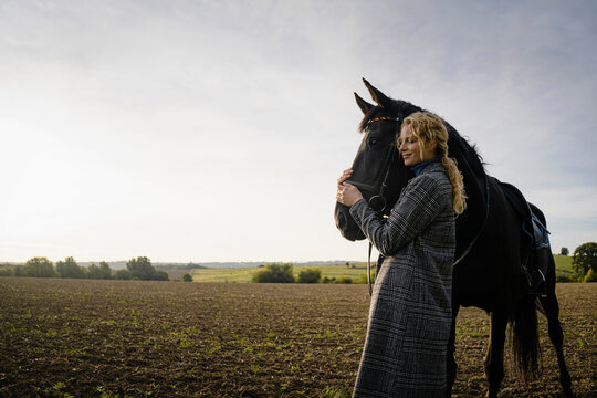 Affectionate young woman with horse on a field in the countryside