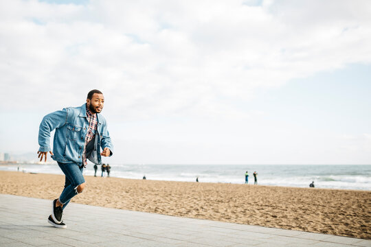 Young man running on beach promenade