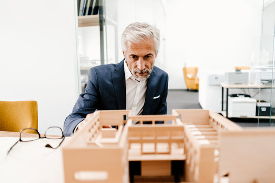 Mature businessman examining architectural model in office