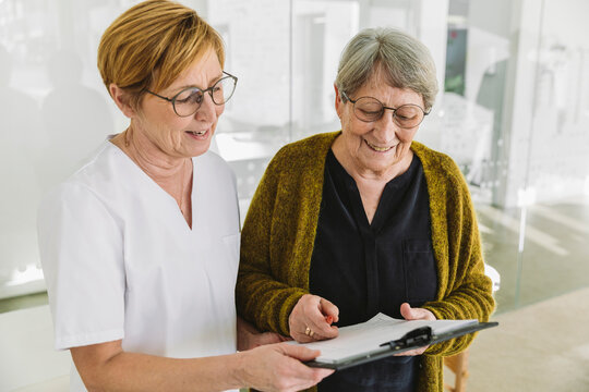 Medical secretary helping senior patient filling out document