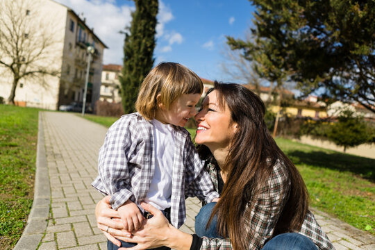 Mother cuddling happy toddler son on a path