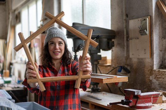 Carpenter holding workpiece in her workshop