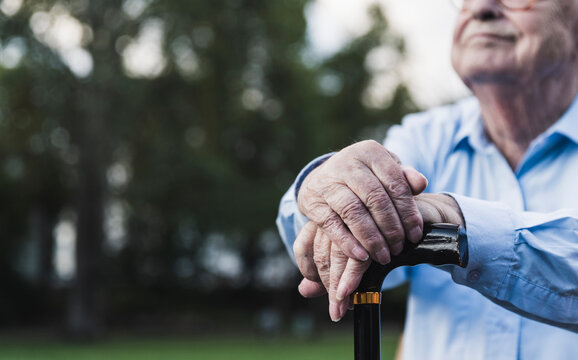 Hands of senior man leaning on walking stick, close-up