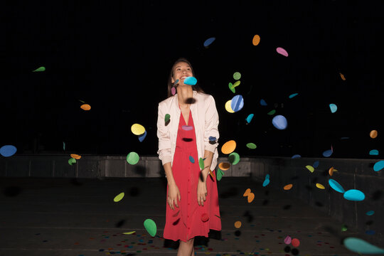 Young woman standing on a rooftop terrace with flying confetti