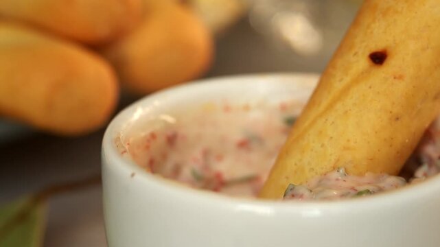 Close up of bread stick is dipped in mayonnaise sauce with spices. Food. Bread