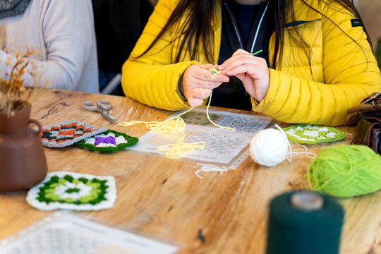 Person crocheting yarn with hook at craft club