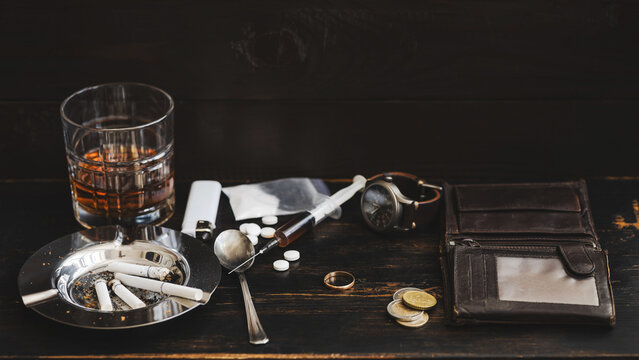 Drug and alcohol addiction concept with heroin syringe, cocaine, pills and wedding ring on wooden table, substance abuse destroying marriage and life