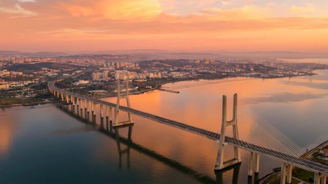 cinematic drone perspective of the cable stayed bridge pillars reflecting in the water at sunset in lisbon video
