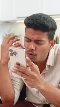 Indian man at home plays mobile game loses round makes facepalm upset yet ready for rematch. Arabian guy on sofa taps try again on smartphone plans comeback focuses on next level and score recovery
