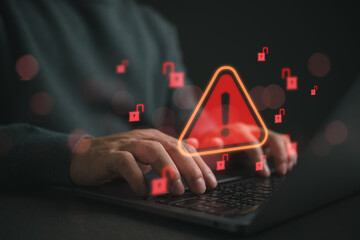 Hands typing on laptop with cybersecurity warning alert and unlocked padlock icons. Data breach...
