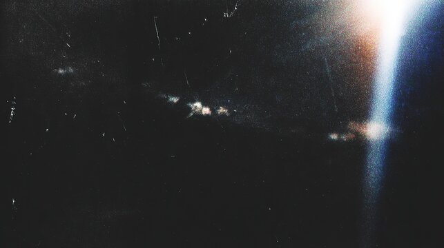 Retro distressed film effect with scratches, dust particles and light leaks. Noisy grain texture with light leak flares on black background.